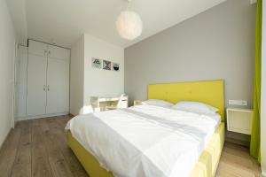 een slaapkamer met een groot bed met een geel hoofdeinde bij ART Apartment in Târgu-Mureş