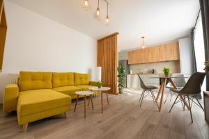 a living room with a yellow couch and a kitchen at ART Apartment in Târgu-Mureş