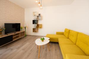 a living room with a yellow couch and a tv at ART Apartment in Târgu-Mureş