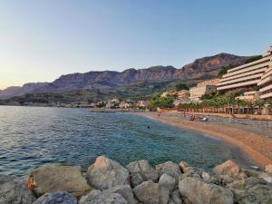 a beach with rocks in the water and buildings at Apartmani Barešić in Podgora
