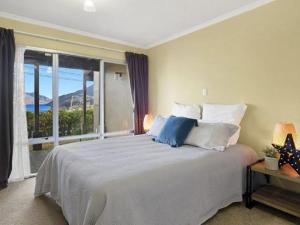 ein Schlafzimmer mit einem großen Bett und einem großen Fenster in der Unterkunft ULTIMATE CONVENIENCE, WALK-TO-TOWN TOWNHOUSE in Queenstown