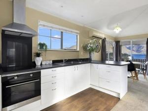 a kitchen with white cabinets and a black stove top oven at ULTIMATE CONVENIENCE, WALK-TO-TOWN TOWNHOUSE in Queenstown +6 photos