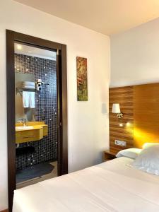 a bedroom with a bed and a bathroom with a sink at Hotel Spa QH Centro León in León