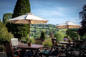 two tables and chairs with umbrellas on a patio at Burleigh Court Hotel in Stroud