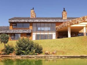 a house on a hill next to a body of water at Amberley Mountain Reserve in Dullstroom