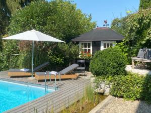 a swimming pool with an umbrella and a house at Landhaus am Plattenbichl - Luxus Apartment mit Pool und Sauna - im Sommer Bergbahn inklusive in Oberstdorf