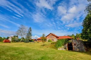 an old stone house on a grassy field at Winnica "Żabi Raj" in Skarszewy