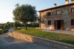 una casa de piedra con dos sillas delante en Tenuta Toscanità, en Cavriglia