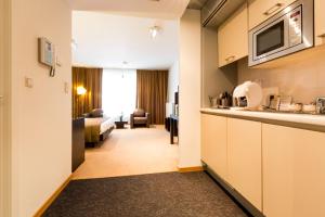 um quarto de hotel com uma cozinha e uma sala de estar em Diamant Suites Brussels EU em Bruxelas