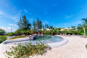 a swimming pool with umbrellas in a resort at Seahorse @ Swan Villas in Placencia