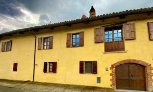 un edificio amarillo con ventanas y garaje en Bed and Breakfast La Volpe tra le Vigne, en Castelnuovo Don Bosco