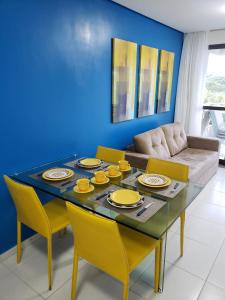 une table à manger avec des chaises jaunes et un mur bleu dans l'établissement Carneiros Beach Resort - Apto 214D, à Tamandaré