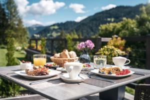 a table with plates of food and drinks on it at Les Dolomites Mountain Lodges in San Martino in Badia