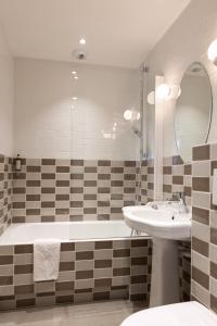 La salle de bains est pourvue d'une baignoire, d'un lavabo et d'un miroir. dans l'établissement Hôtel des 3 Poussins, à Paris