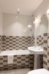 a bathroom with a tub and a sink and a mirror at Hôtel des 3 Poussins in Paris