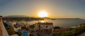 una puesta de sol sobre una ciudad con casas y el agua en Manos Apartments, en Almyrida