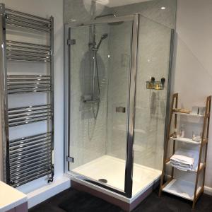La salle de bains est pourvue d'une douche avec une porte en verre. dans l'établissement The Hollow Bed and Breakfast, à Great Longstone