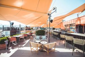 eine Dachterrasse mit Tischen, Stühlen und Sonnenschirmen in der Unterkunft Storchen Zürich - Lifestyle boutique Hotel in Zürich