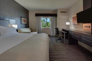 a hotel room with a bed and a desk at Holiday Inn Express & Suites Naples Downtown - 5th Avenue by IHG in Naples
