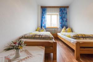 a bedroom with two beds and a vase of flowers on a table at Almliesl HOLL-304 in Hollersbach im Pinzgau