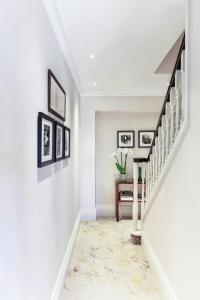 a hallway with white walls and a staircase with a rug at The Langham London in London