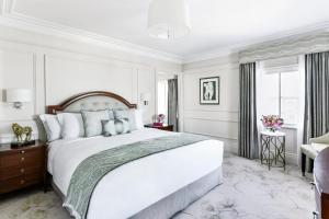 a bedroom with a large white bed and a window at The Langham London in London