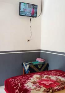 a bedroom with a bed and a tv on the wall at Homestay Anggun Bromo in Bromo