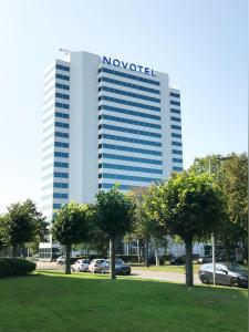 a row of palm trees in front of a large building at Novotel Rotterdam Brainpark in Rotterdam