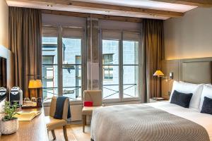 a hotel room with a bed and a large window at Hôtel Les Armures in Geneva
