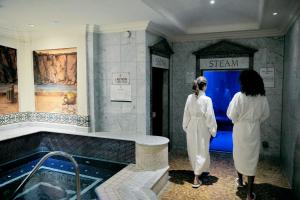 Dos mujeres de pie en un baño mirando una bañera en The Celtic Manor Resort, en Newport