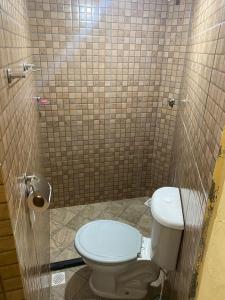 a bathroom with a toilet and a tiled wall at Hospedagem Mariano in Arraial do Cabo