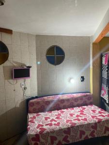 um quarto com uma cama com um cobertor vermelho e branco em Hospedagem Mariano em Arraial do Cabo