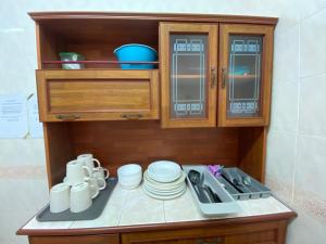 a kitchen with wooden cabinets and white dishes on a counter at Cameron Highland Cozy Homestay in Tanah Rata