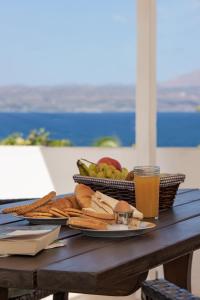 a picnic table with a plate of food and a drink at Manos Apartments in Almyrida