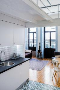 uma cozinha e sala de estar com um lavatório e uma mesa em Oporto City View - Trindade no Porto