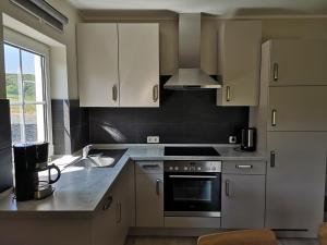 a kitchen with white cabinets and a stove top oven at Hubertushof Eifel in Schönbach