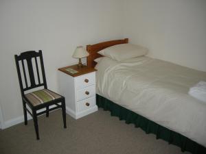 a bedroom with a bed and a chair and a nightstand at Lovelace in Porlock