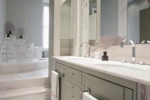 a white bathroom with two sinks and a tub at The Presidential Suite in Trieste