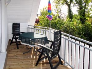 a table and chairs on a porch with a rainbow umbrella at Apartment Scholz by Interhome in Born