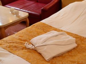 a white robe sitting on a bed next to a table at Hotel Fine Garden Matsuyama in Matsuyama +21 photos