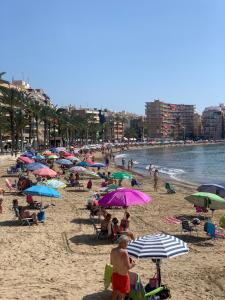 eine Gruppe von Menschen mit Sonnenschirmen an einem Strand in der Unterkunft Luxury beach apartment in Torrevieja