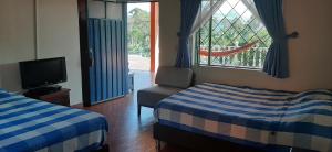 a room with two beds and a tv and a window at Las Mercedes Finca Cafetera in Cumaca