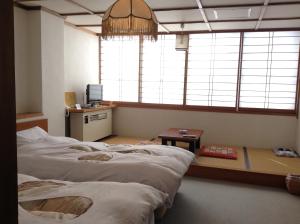 um quarto com duas camas, uma mesa e janelas em Resort Inn Chitose em Nozawa Onsen