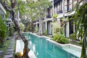 a swimming pool in front of a building with trees at S'cape Condotel in Sanur