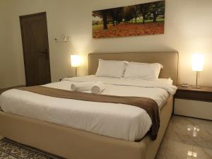 a bedroom with a large bed with two lamps at Muscat Royal Suites in Seeb