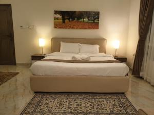 a bedroom with a large bed with two lamps at Muscat Royal Suites in Seeb