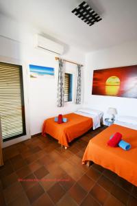 2 Betten in einem Zimmer mit orangefarbener Bettwäsche in der Unterkunft Apartamentos Cas Xurrac in Es Caló