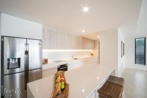 a kitchen with a refrigerator and a bowl of fruit on a counter at Splendeur Sur La Mer Premiere in Airlie Beach