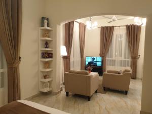 a living room with two chairs and a television at Muscat Royal Suites in Seeb