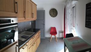 a kitchen with a red chair and a clock on the wall at LE PONT NEUF 61 in Alençon